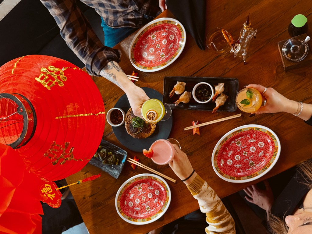 people clinking glasses over a table of food