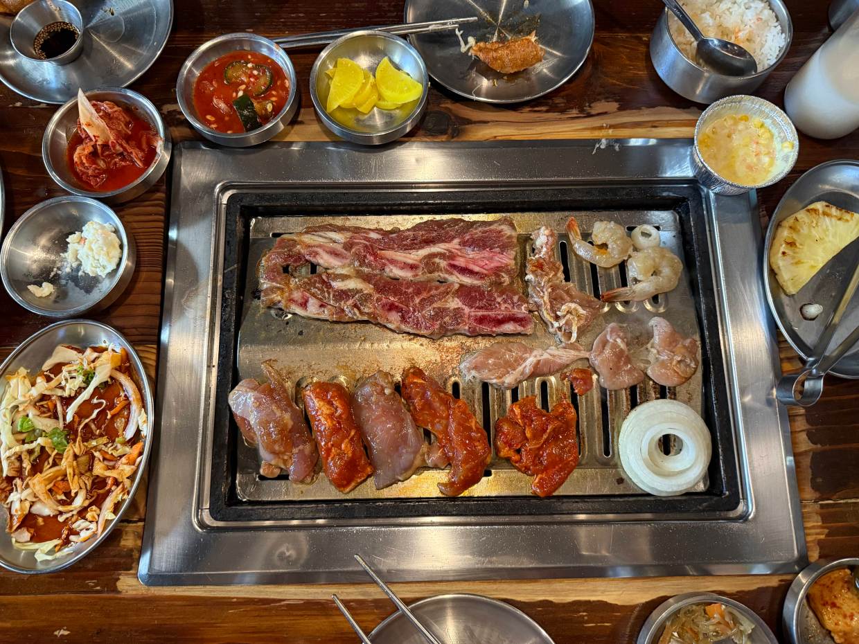 meat on a grill with a variety of banchan