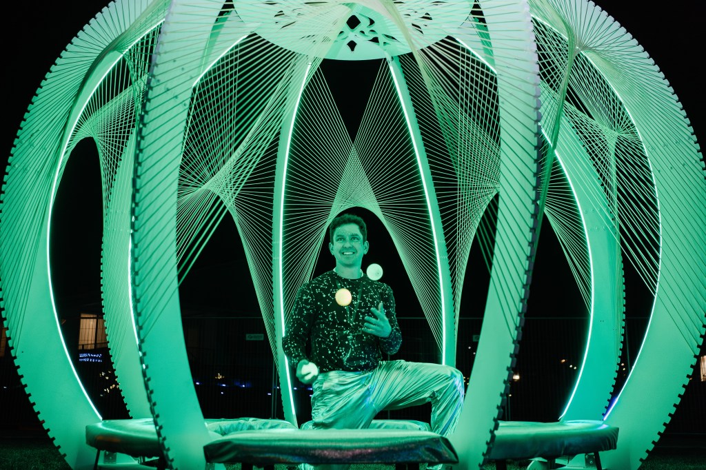 man juggling in green art piece