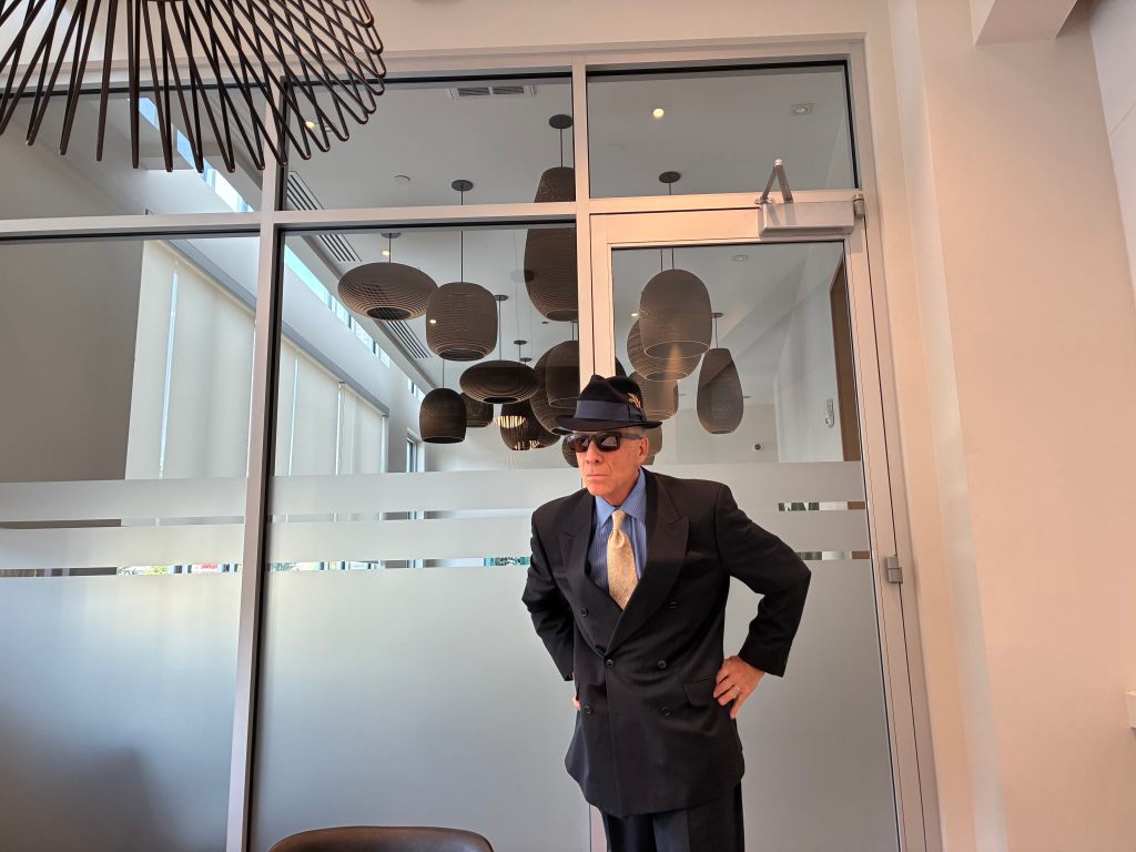 Man stands in a suit and glasses.