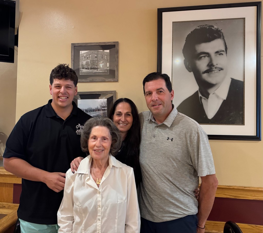 four people posing next to a black and white photo