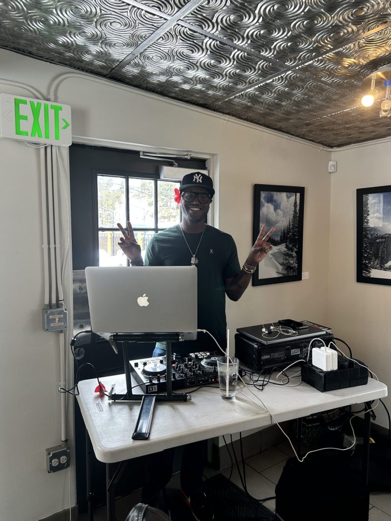 a smiling man standing next to a computer and recording equipment