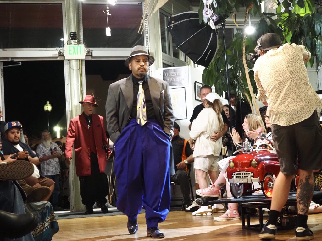 A man in a zoot suit walks a runway