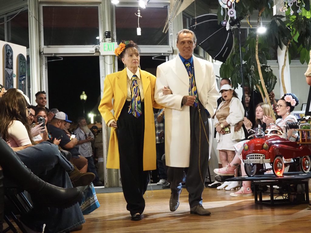 A couple in zoot suits walks a runway