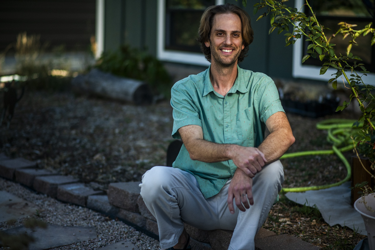 man in green shirt outside by plant