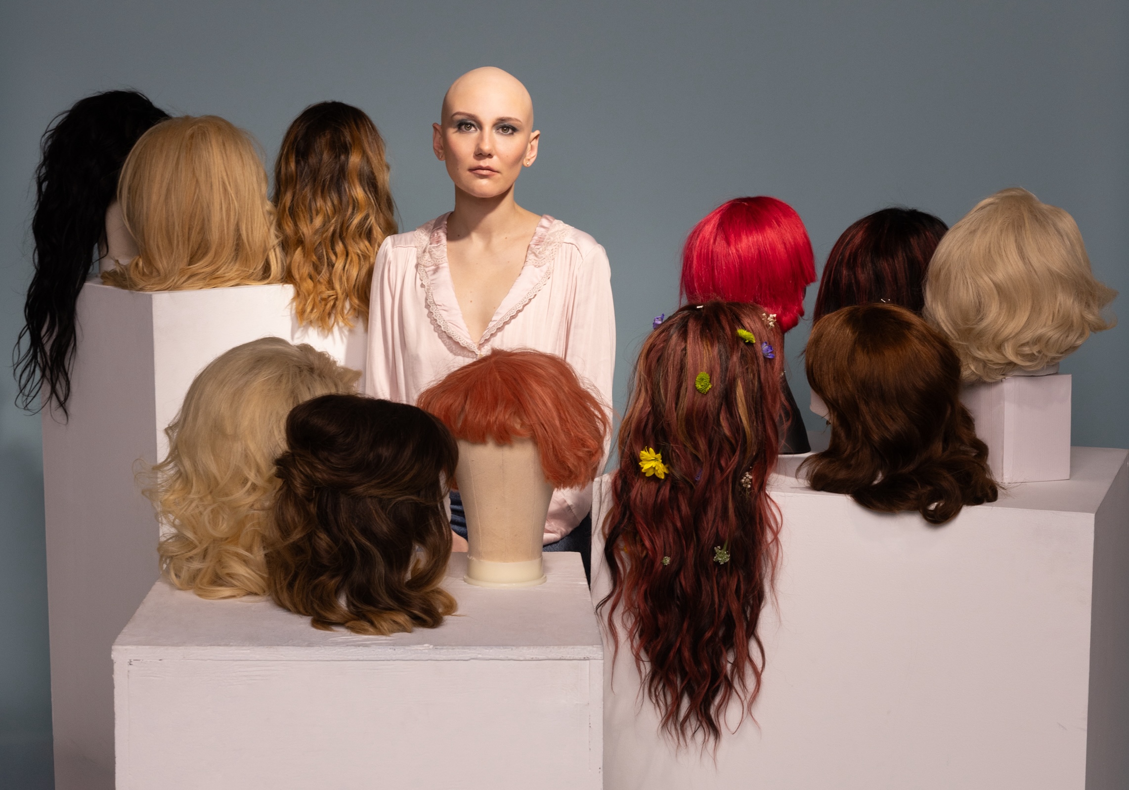 Molly Tuttle standing with wigs around her