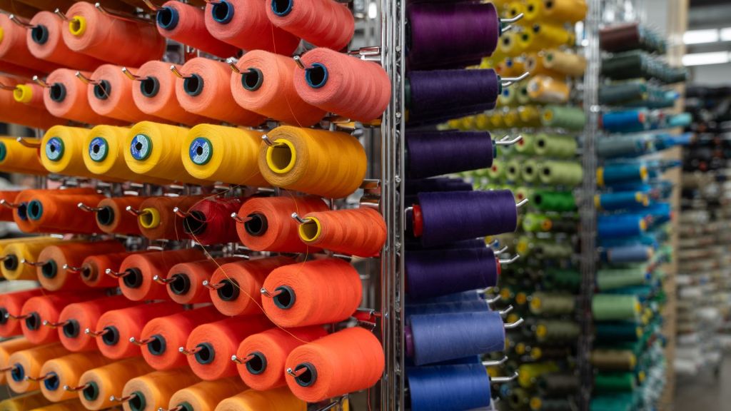 Dozens of colorful spools of thread on metal racks