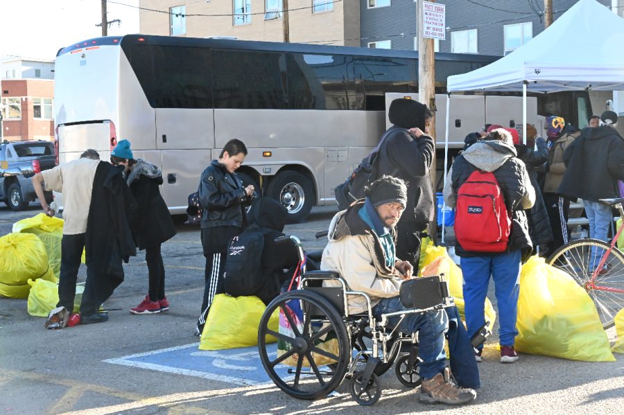 People get on a bus to go to a hotel shelter in Denver.
