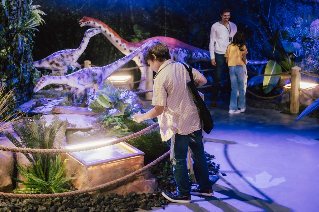 A kid looks at a dinosaur exhibit.