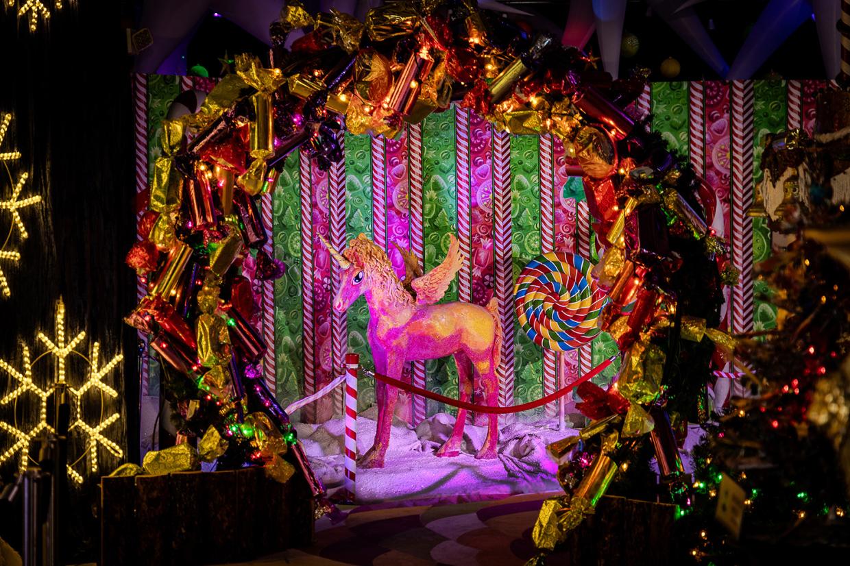 A pink unicorn is surrounded by Christmas decor.
