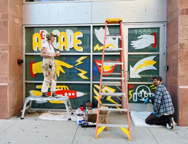 Storefront windows painted with images of hands, lightning, and a rocket ship.