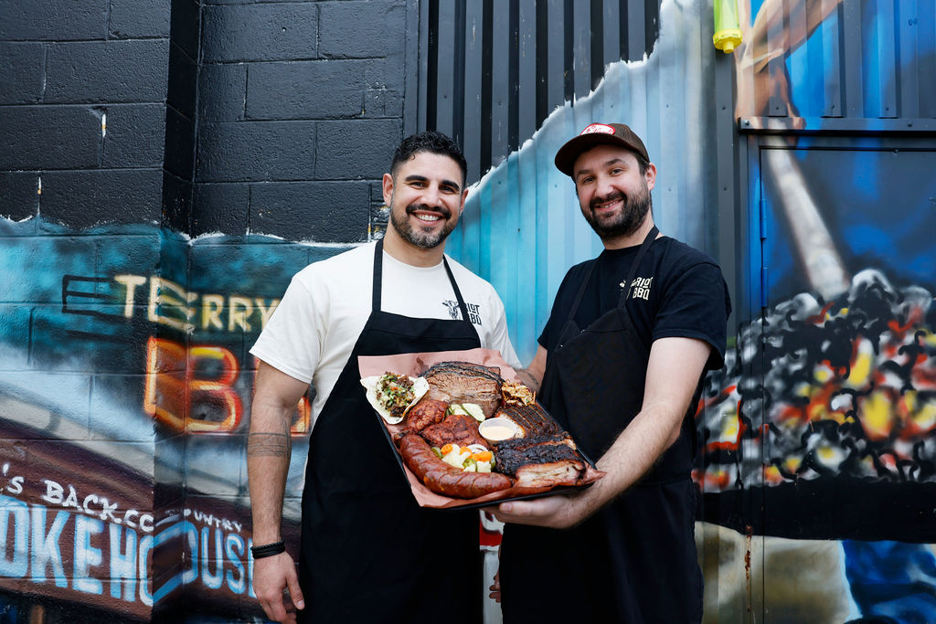 two men holding a tray of BBQ