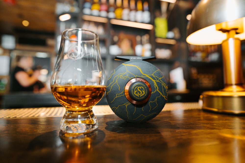 a glass of whiskey next to a fishing reel