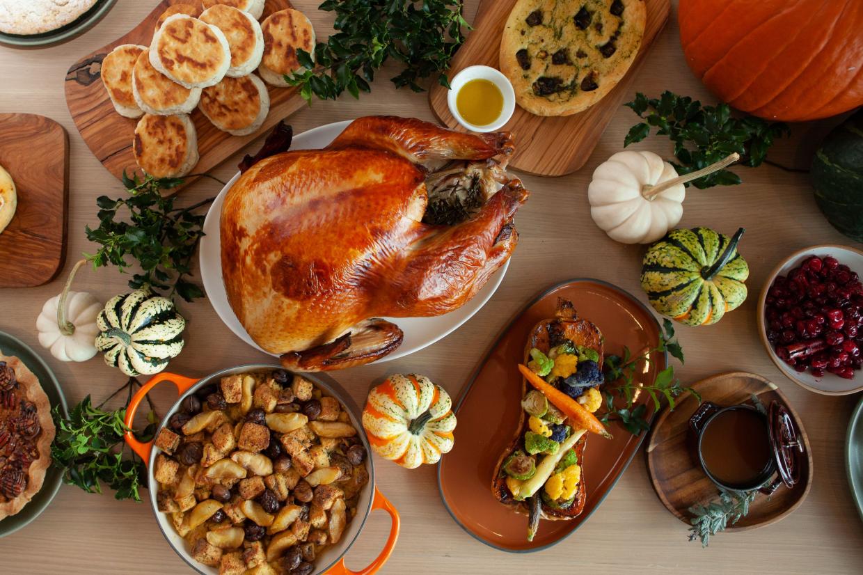 An overhead shot of a whole cooked turkey, roasted butternut squash, biscuits and more from Saverina