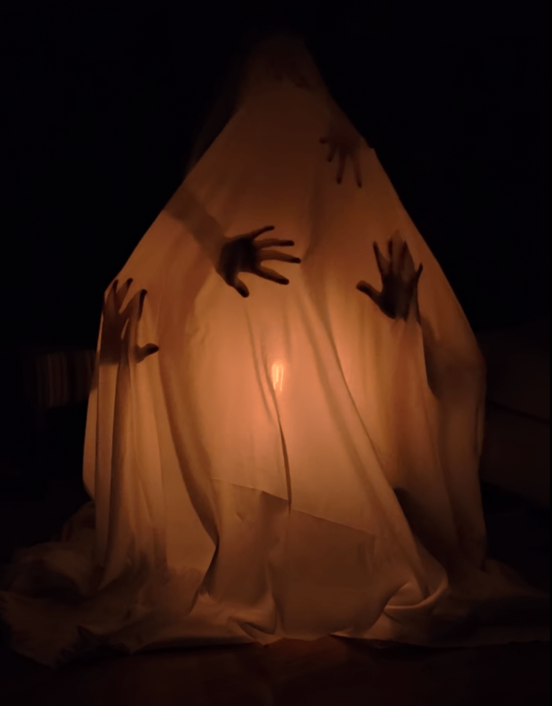 Hands push underneath a cloth in an attempt to escape.