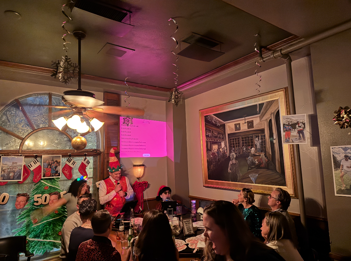 People gathered around a man dressed as an elf in a restaurant