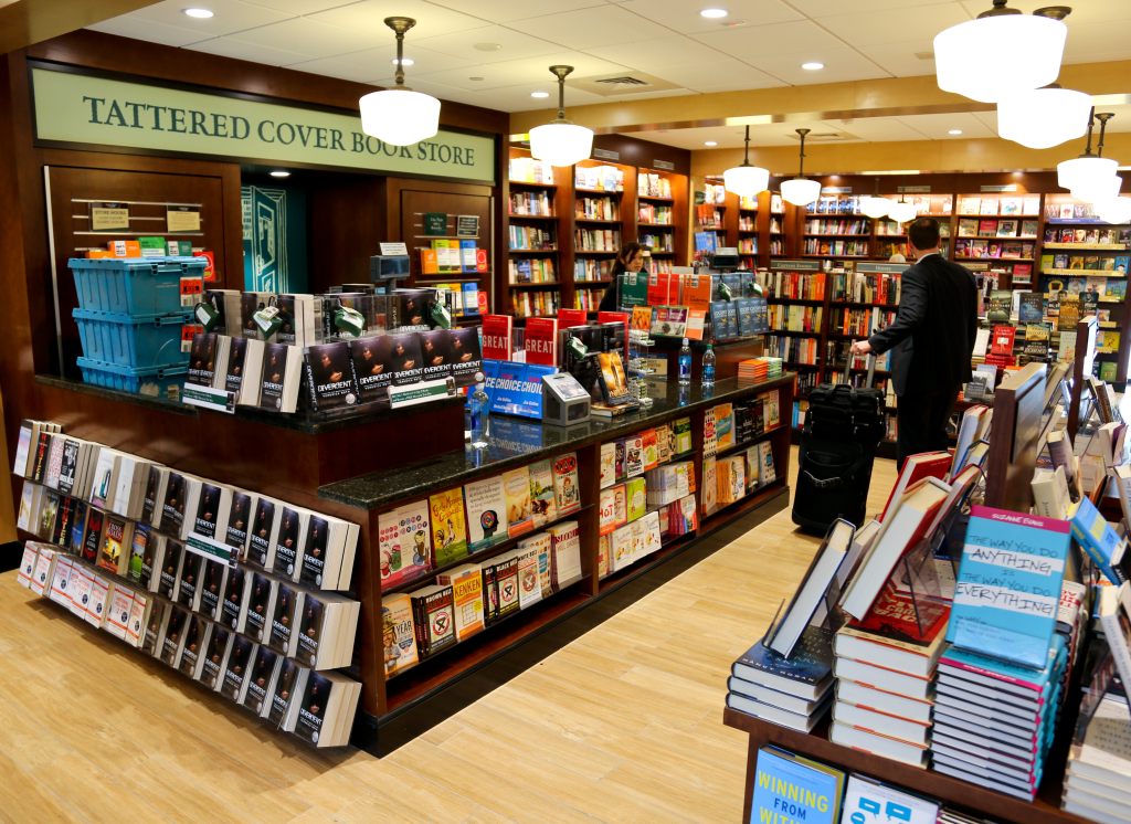 Interior of a bookstore with shelves filled with books, a checkout counter, and a customer browsing.