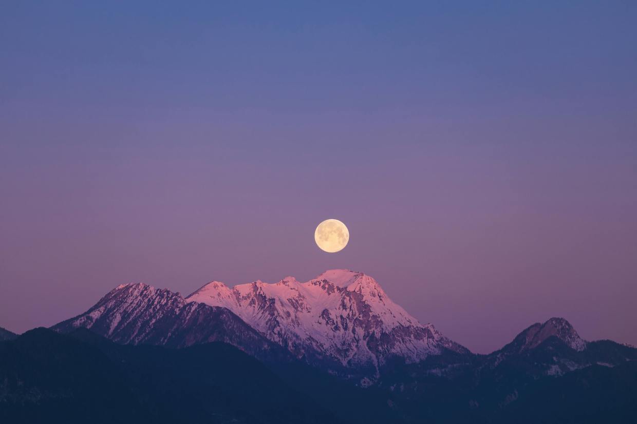 A moon rising over mountains