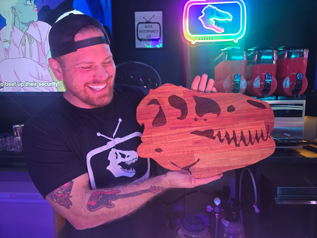 man holding t-rex-shaped wooden board