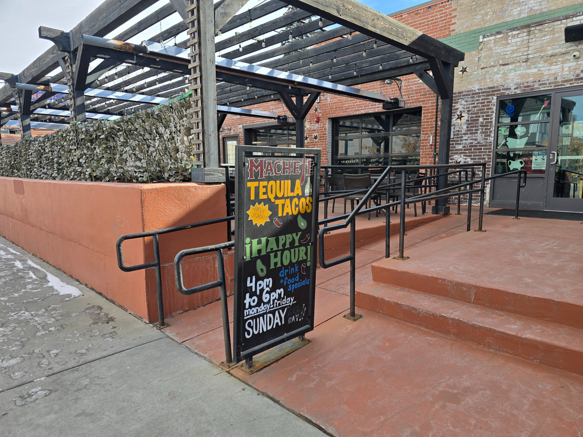 happy hour sandwich board outside a patio
