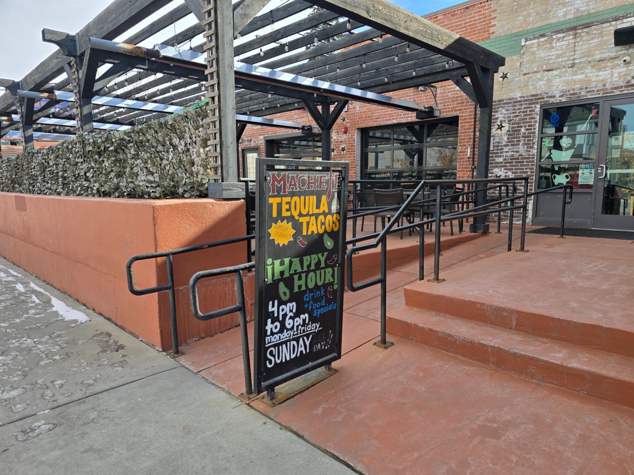 happy hour sandwich board outside a patio