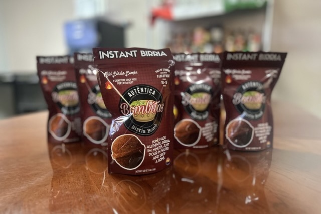Maroon packages of Bombitas birria bomb, featuring a graphic of the sphere-pressed spice blend