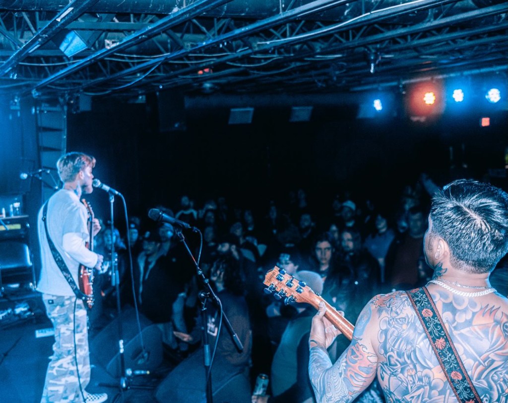 Two guitar players on stage in front of an audience