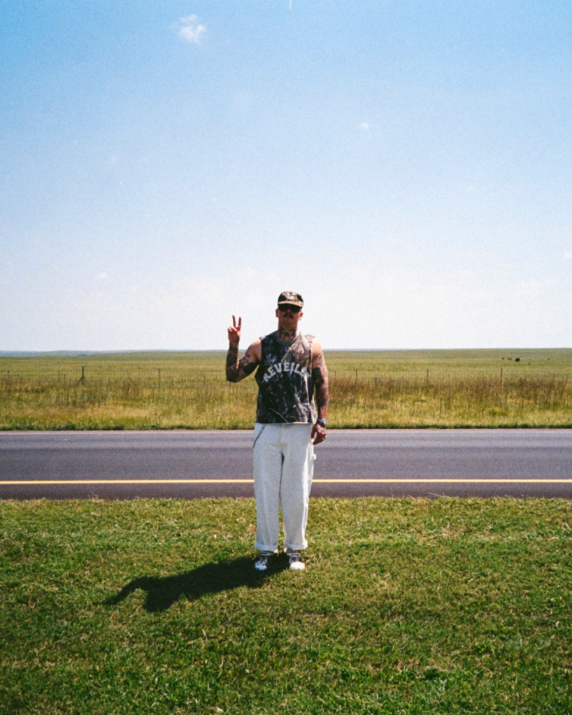 man standing next to a road with a peace sign