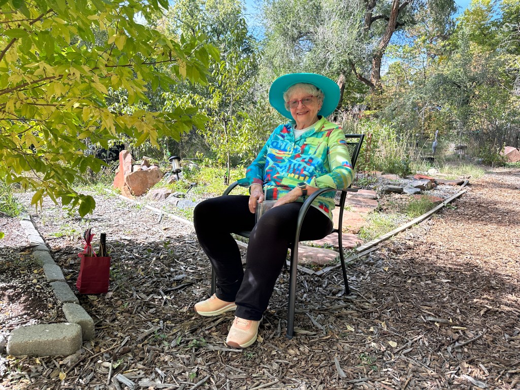 Linda Graham sits in a chair in her garden