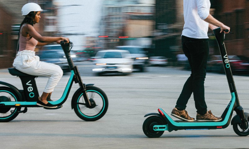 People ride on e-scooter and e-bike through the city