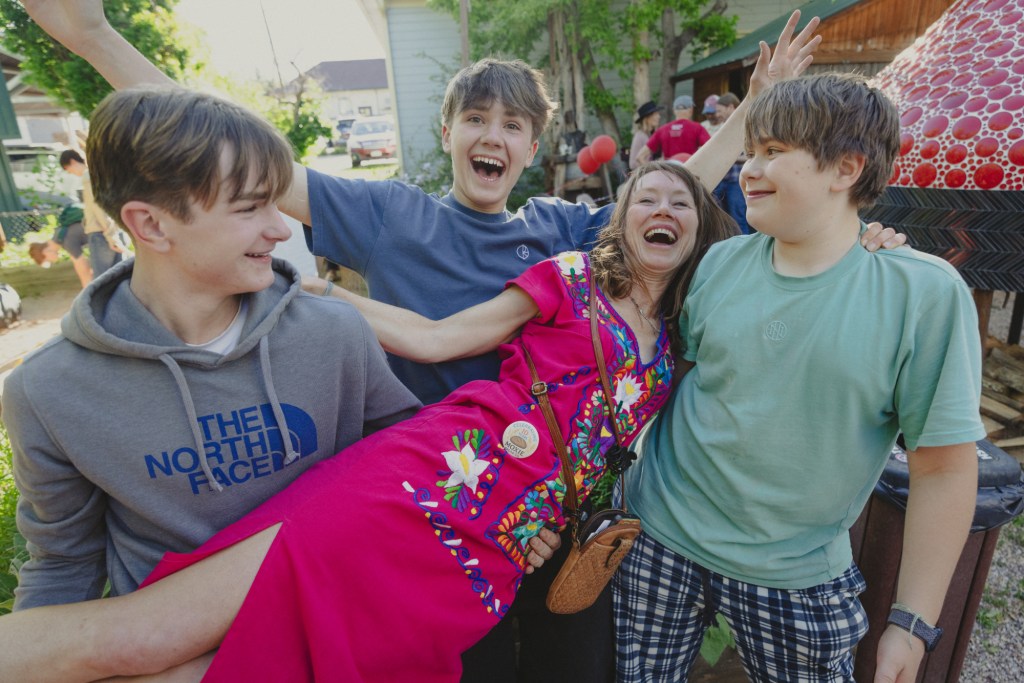 woman in a pink dress with three young men
