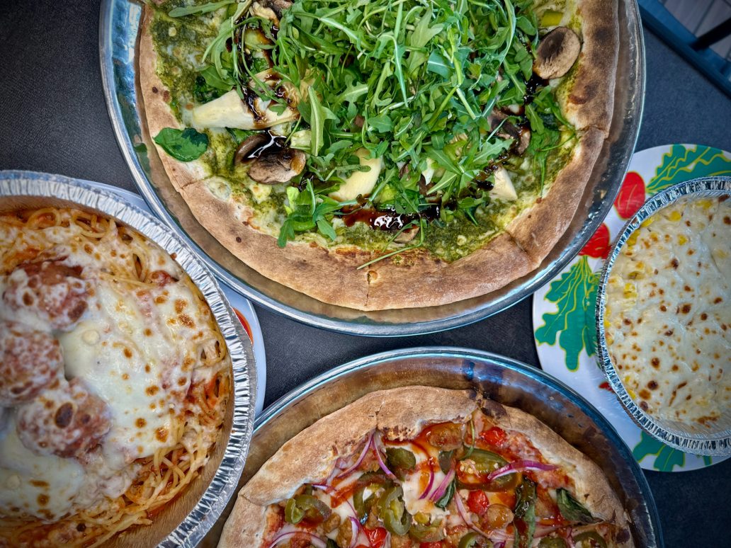 pizza topped with arugula and various sides