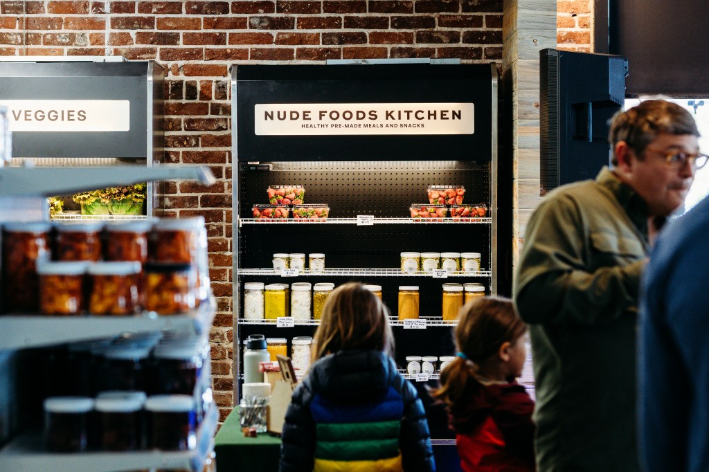 Customers in front of the ready-made meals refrigerator at Nude Foods Market