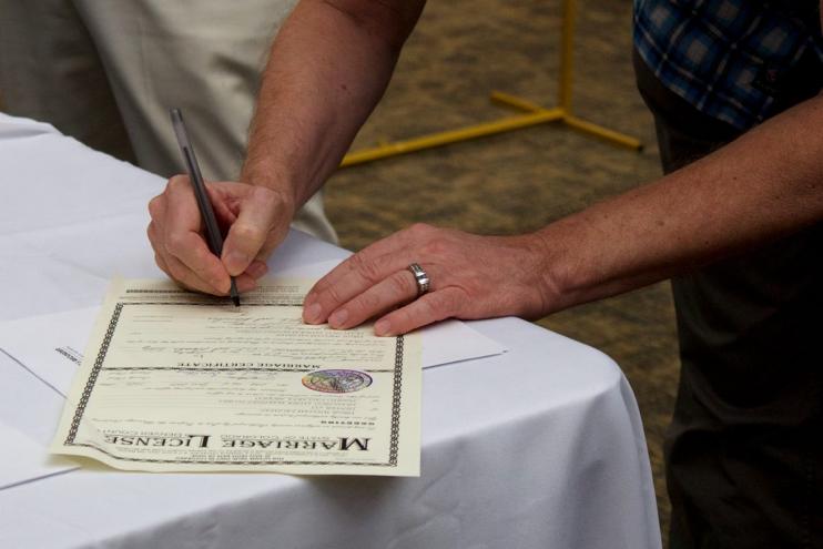 A man signs his marriage license during Denver's annual marriage marathon event in 2025.