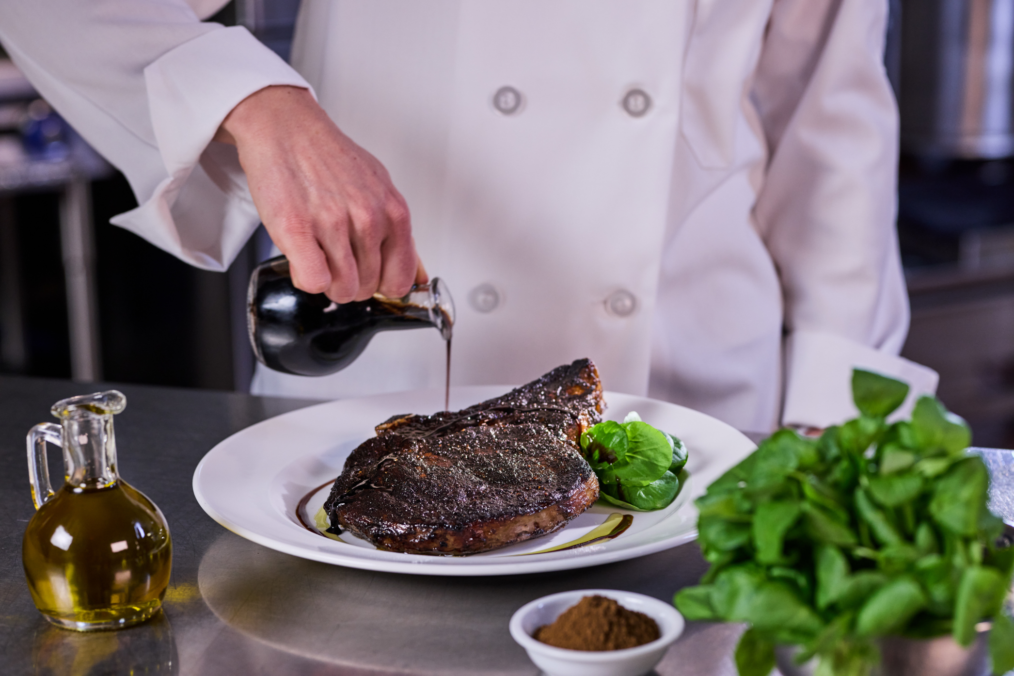 chef pouring sauce onto a steak