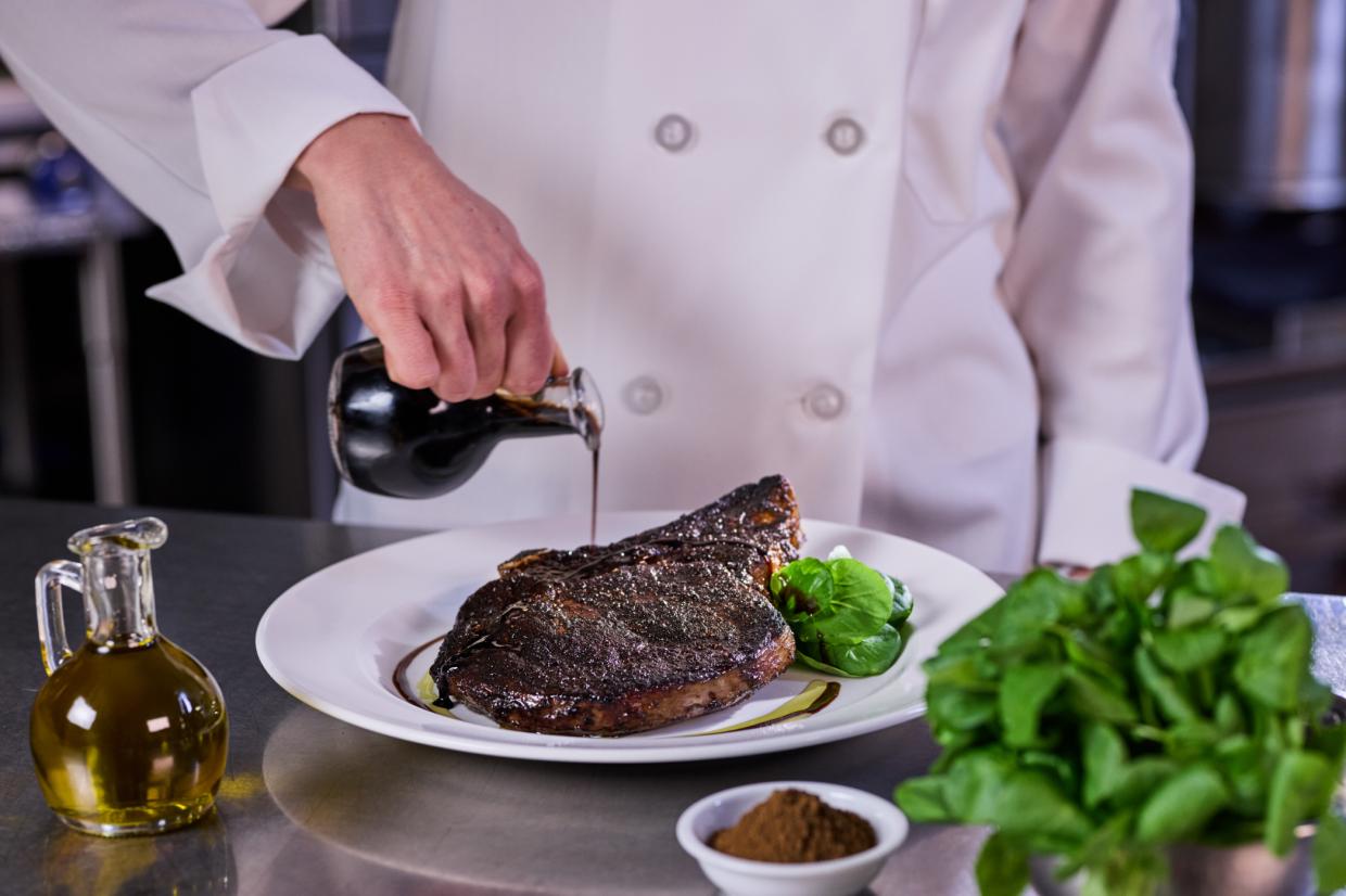 chef pouring sauce onto a steak