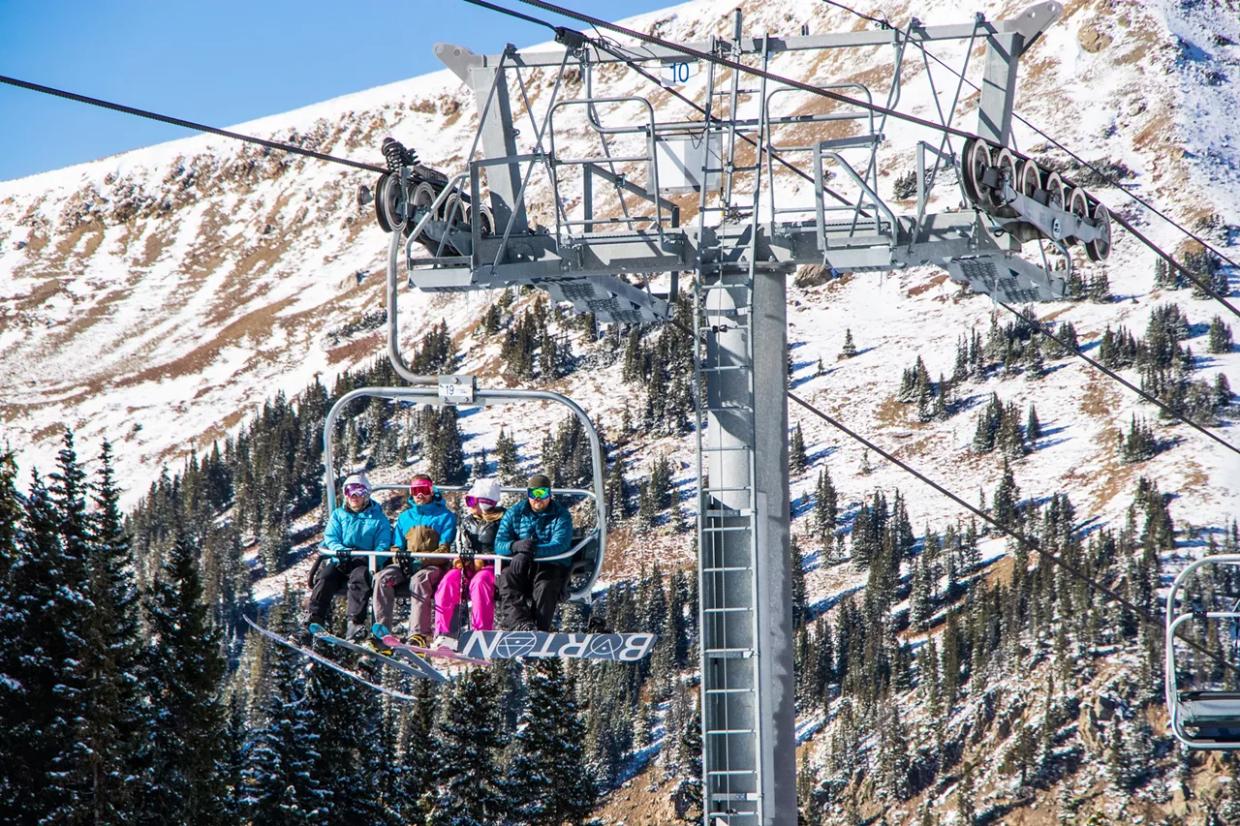 Skiers and snowboarders take a lift in Arapahoe Basin ski area.