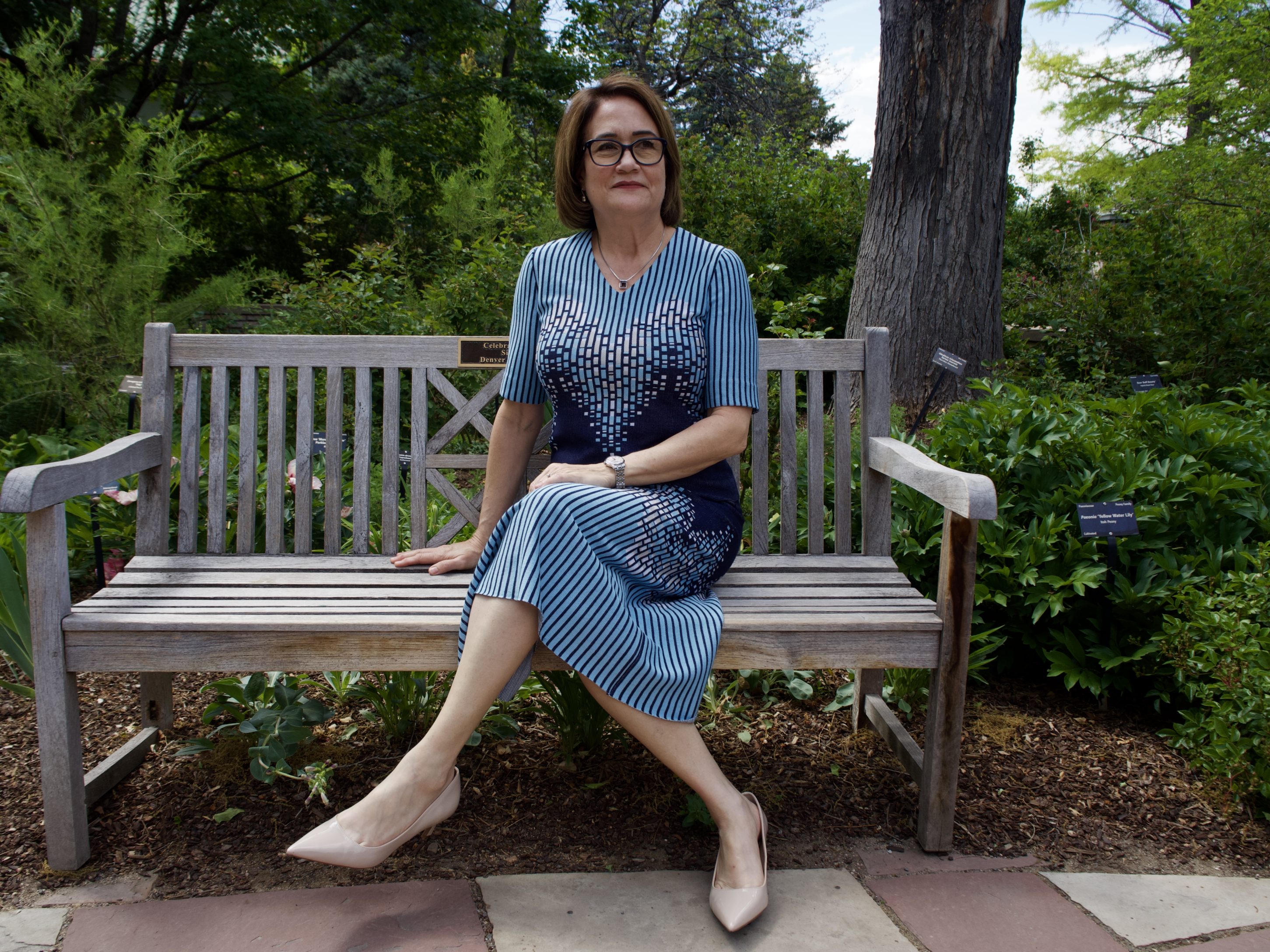 CEO of Denver Botanic Gardens Donna McGinnis sits on a bench in the gardens.
