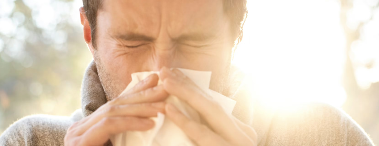 man sneezes into a tissue