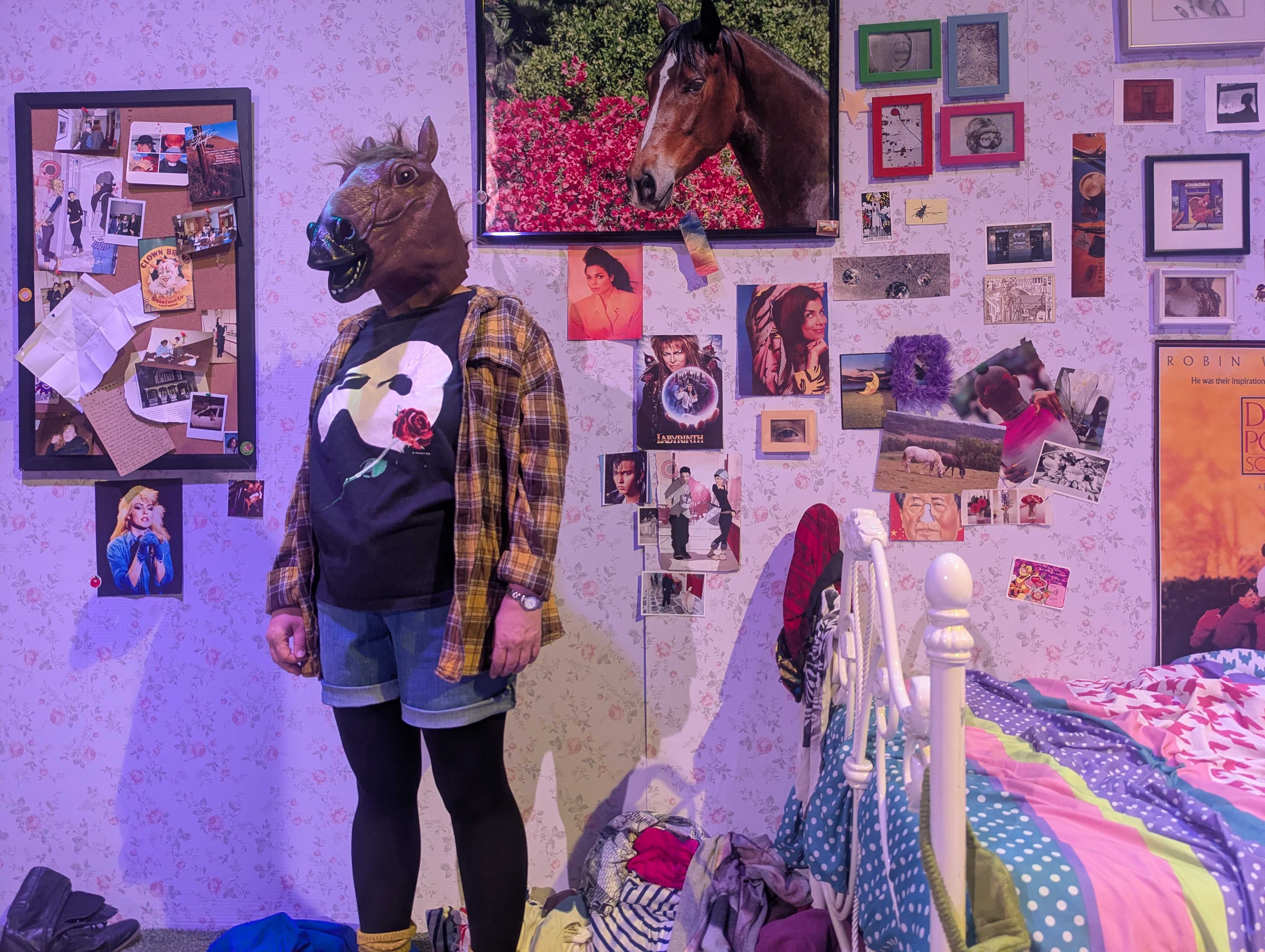 A woman in a horse mask stands in a busy bedroom