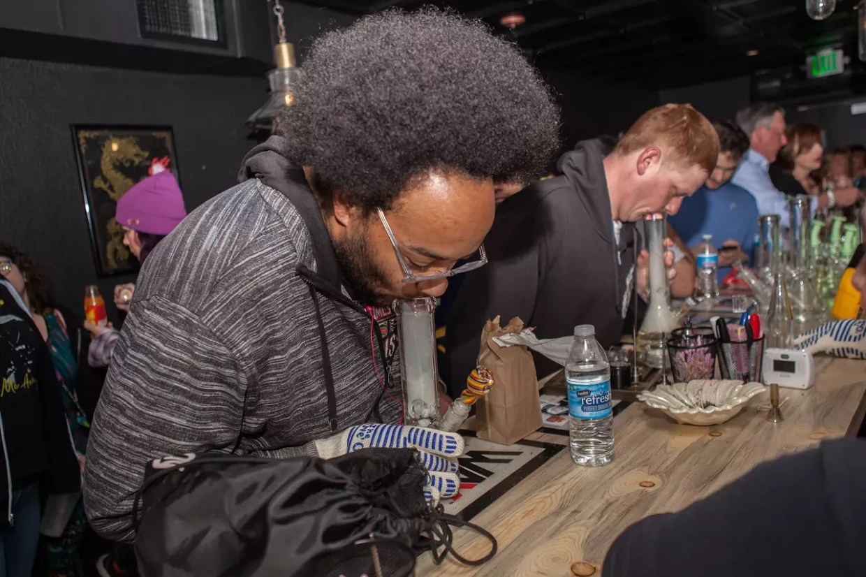 Two men hit bongs at the counter of a now-closed cannabis lounge in Denver.