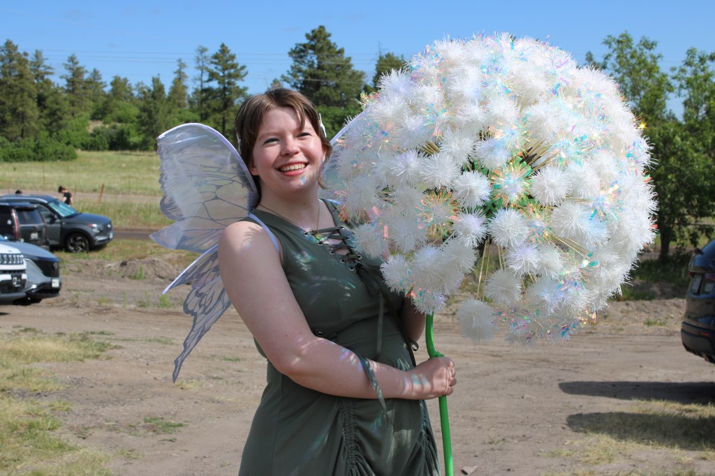 A person in fairy cosplay holds a giant flower