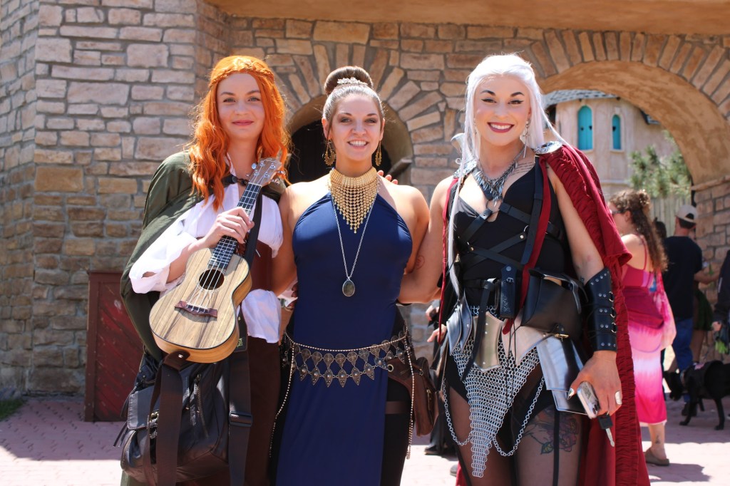 Three woman pose together outside the Ren Faire