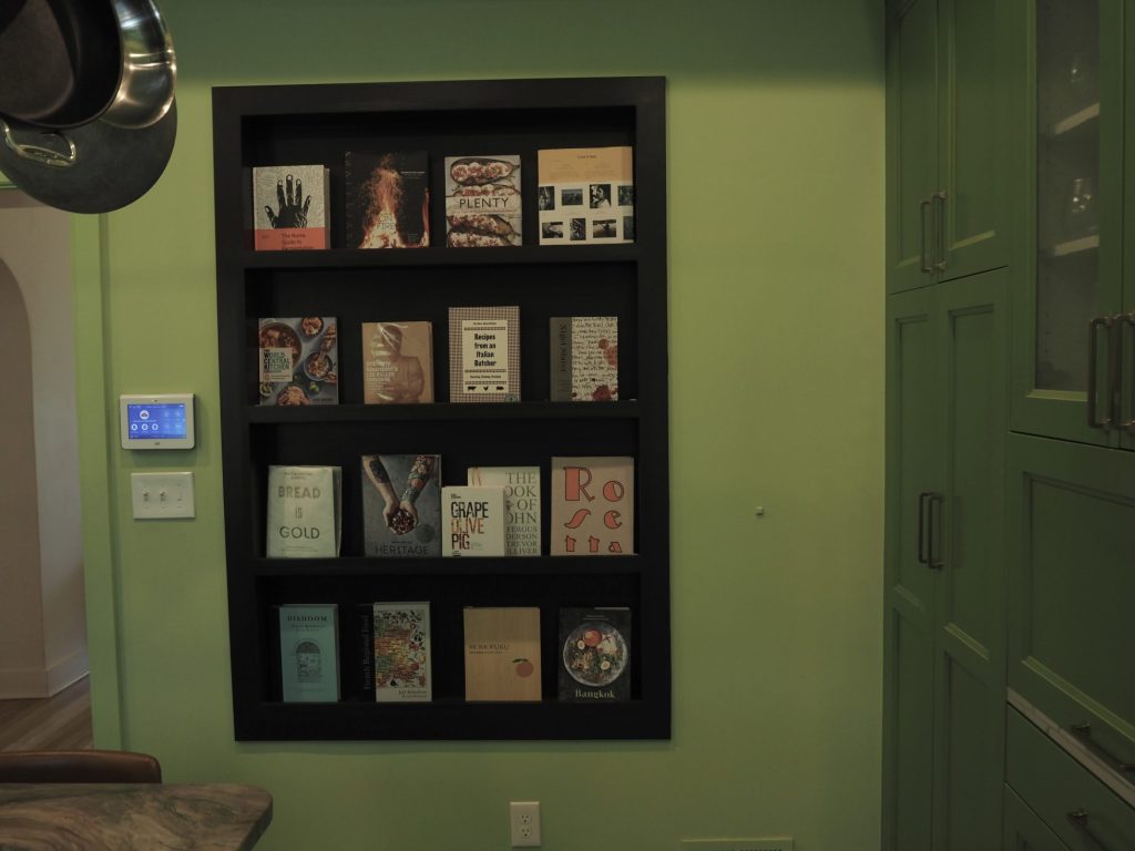 A shelf built into the kitchen wall for cookbooks.