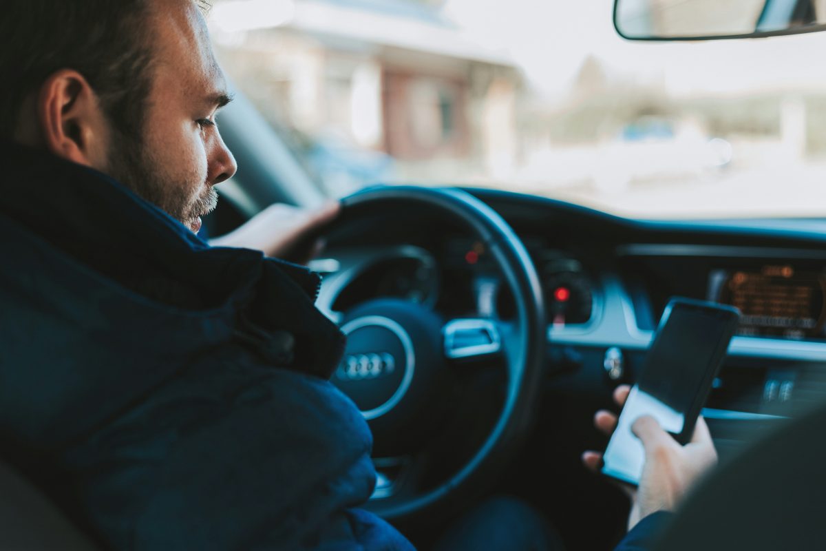 Man looks at his smartphone while driving an Audi
