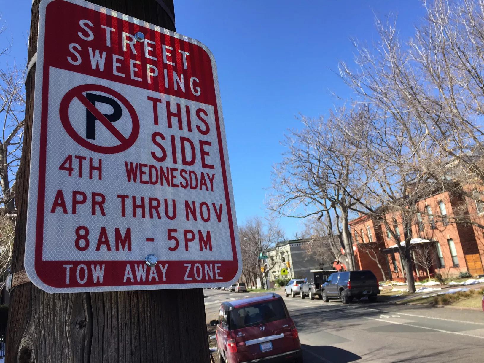 A street sweeping sign bolted to a telephone pole on a Denver street.