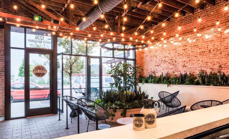 a room with a brick wall, chairs and string lights on the ceiling