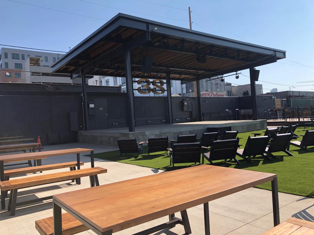 A stage with a black cover sits in front of picnic tables.