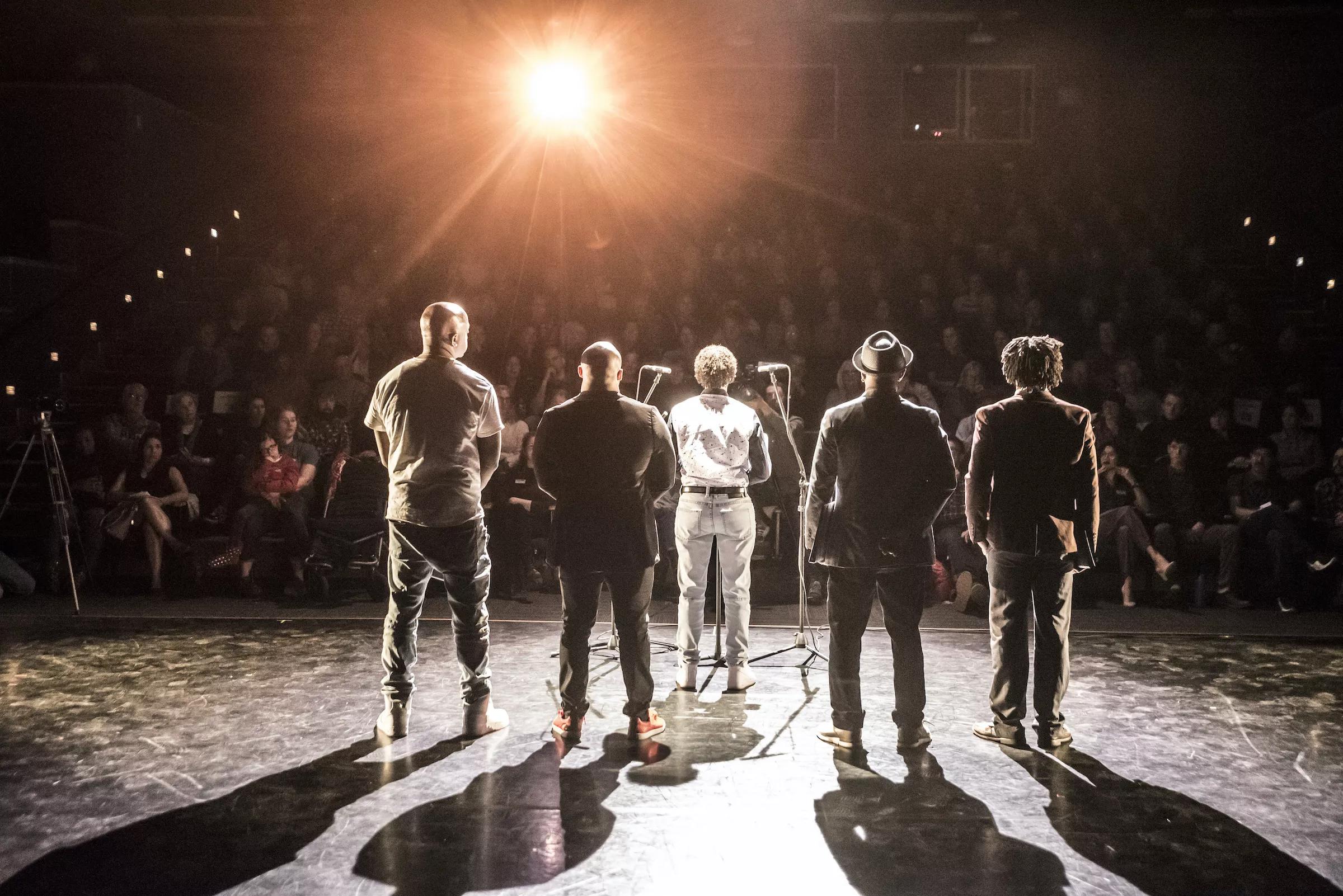 A stage of people with their backs turned