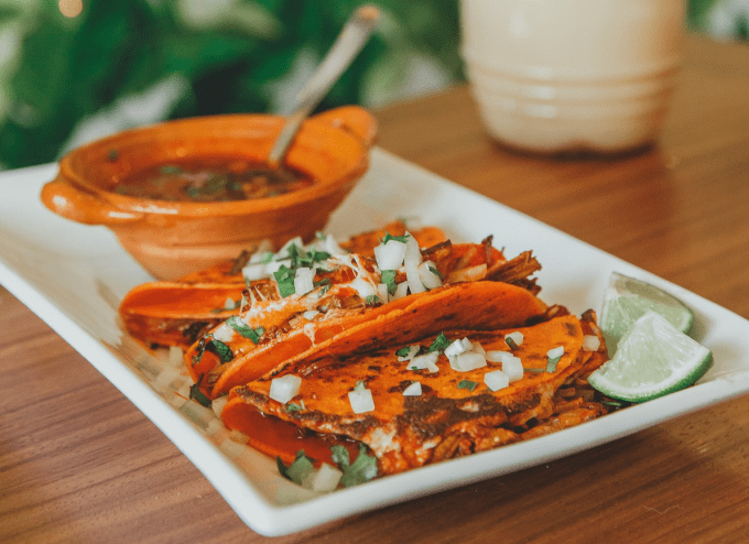 a plate of tacos with onions and cilantro on top
